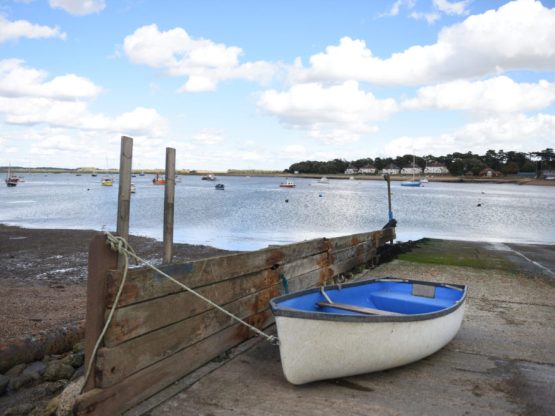 A boat on the shore of the River Deben with the river and blue skies