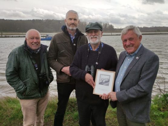 A group of people standing by the river Deben in the background